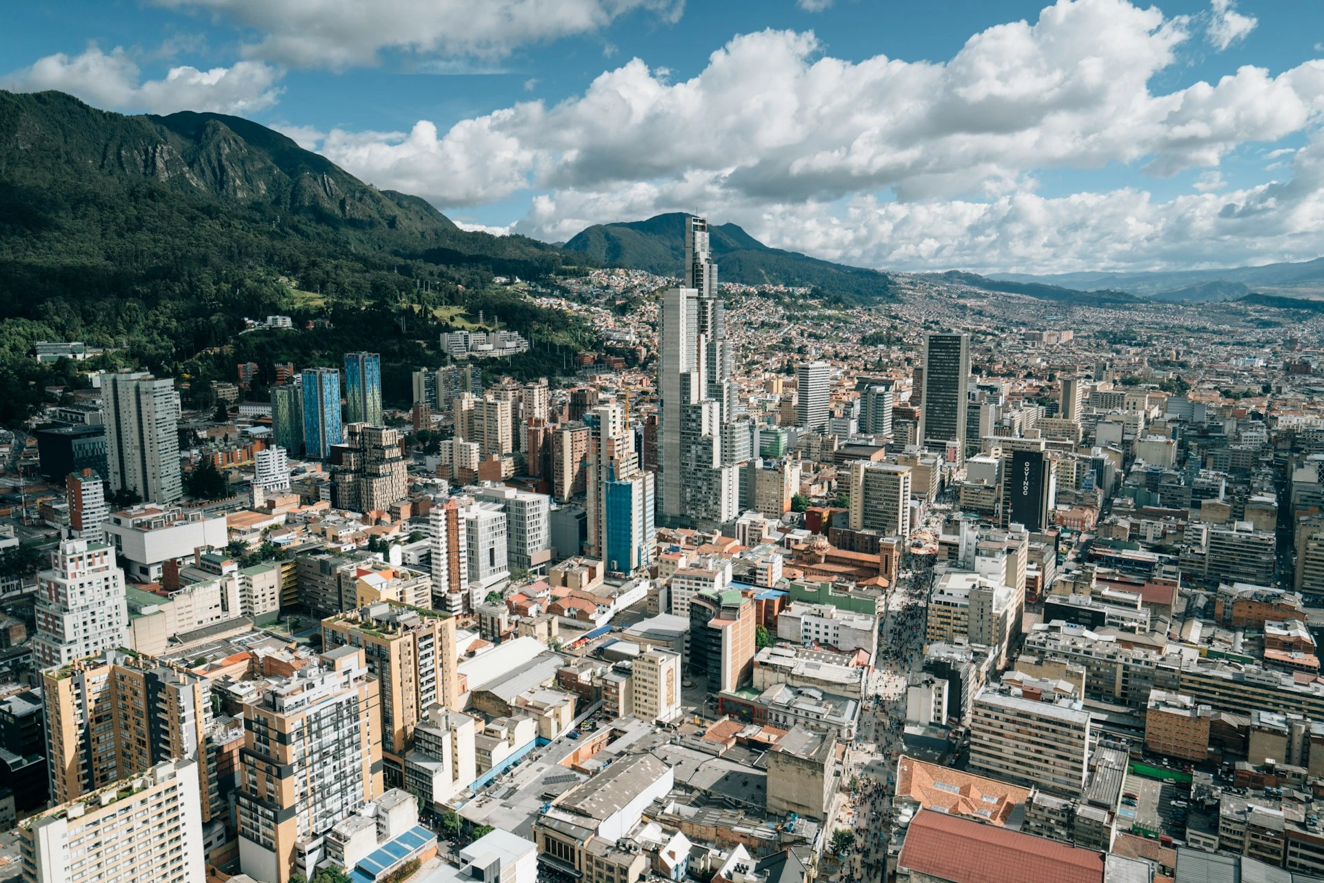 Vista aérea de Bogotá con edificios modernos y montañas al fondo