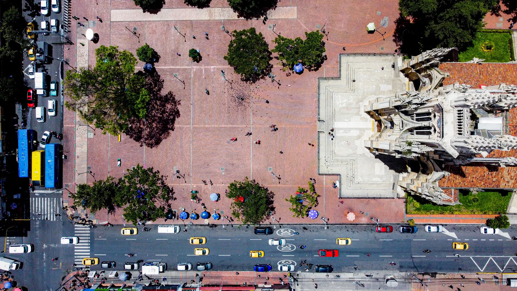 Vista aérea de una plaza en el centro de Bogotá con tráfico de carros, buses y taxis