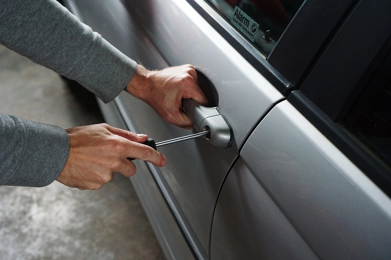 Mecánico anónimo trabajando rodeado de cientos de repuestos de automóviles apilados en un taller oscuro